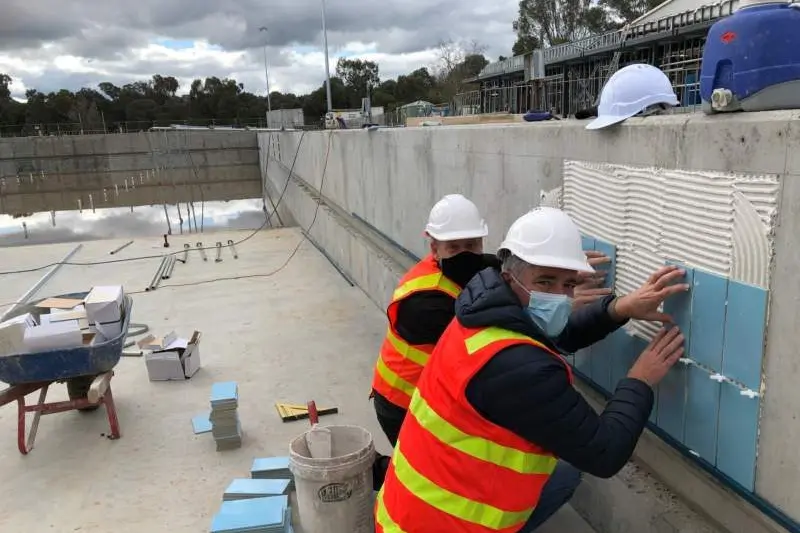 ONWARDS AND UPWARDS: Council chief executive officer Brendan McGrath (left) and mayor Dean Rees put down their pens for some manual labour at Wangaratta\\u2019s much-awaited 50-metre pool. 