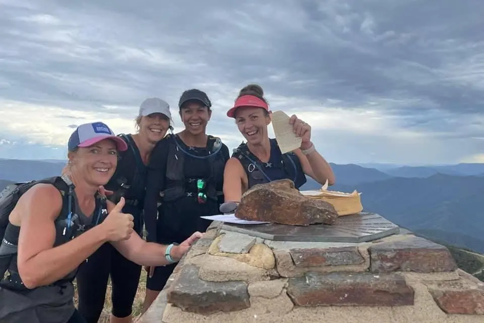 ON TOP OF THE WORLD: Felicity Carmody, Tracy Smith, Lexi Togolo and Kate Harding mark their ascent to the summit of Mount Buller by ripping a page from a book atop the mountain.