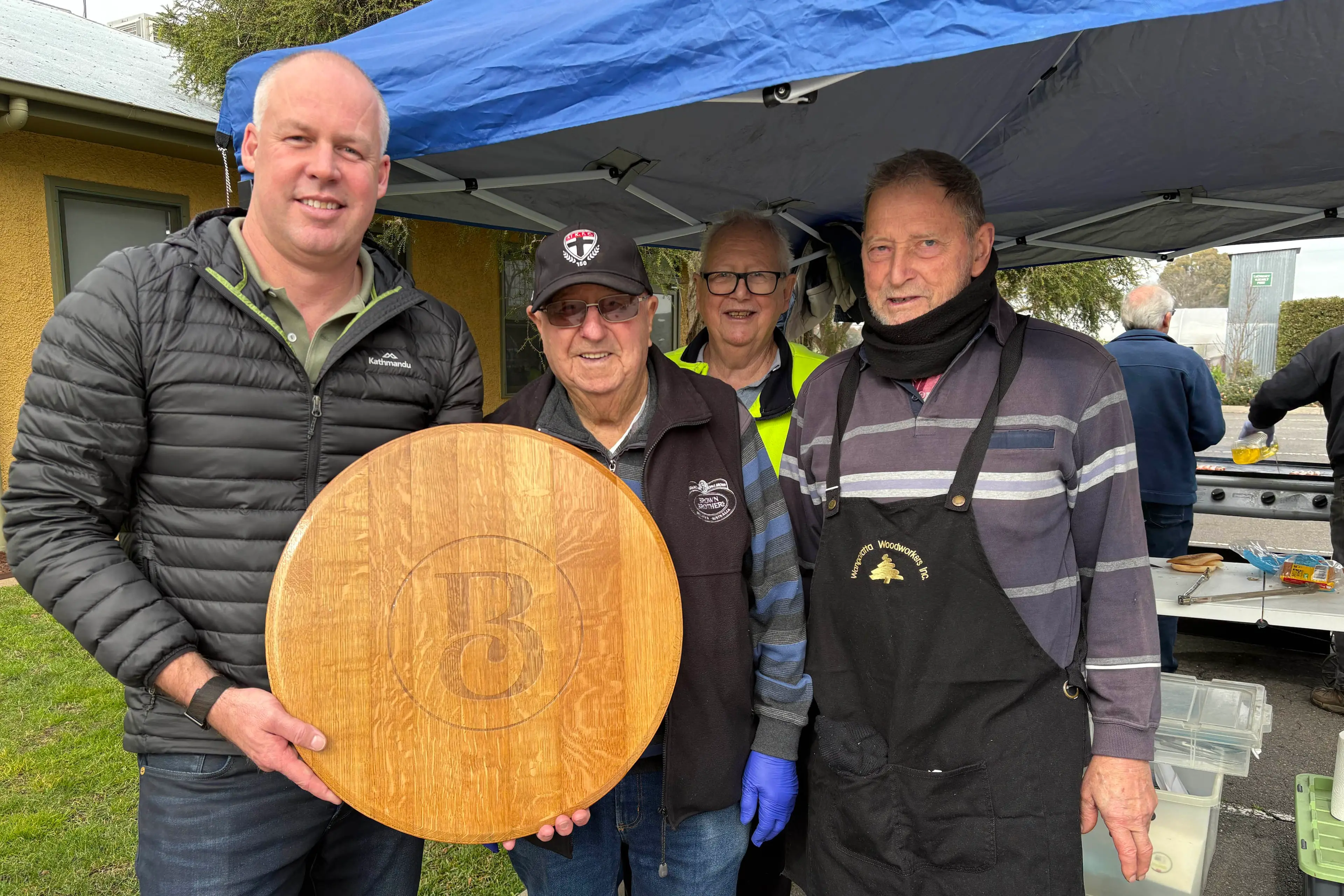 <p>WORKING TOGETHER: Brown Family Wine Group chief operations officer Joel Tilbrook (left) with Wangaratta Woodworkers members Les Whinray, Gary King and Warren Anker at the Jeans for Genes Day sausage sizzle.</p>\\n