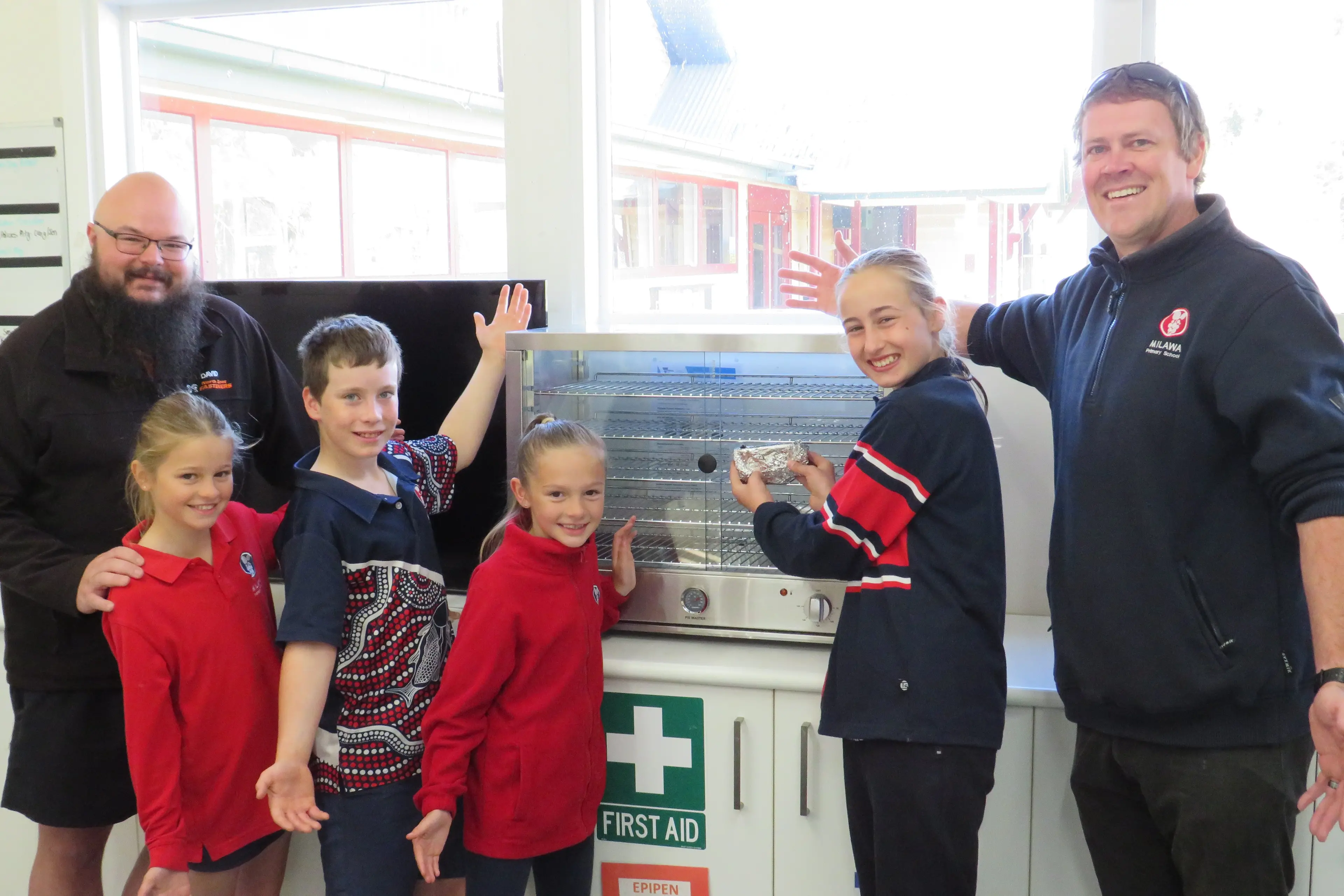 <p>WELCOME DONATION: Dave James from North East Fasteners, Milawa Primary School students Charlotte James (grade five), Cooper Bennett (grade six), Ivy James (grade two) and Anna Conroy (grade six), and acting principal Craig Kerlin, show off the school\\'s new pie-warmer. PHOTO: Simone Kerwin</p>\\n